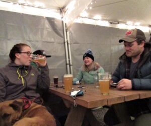 Four people sit at an outdoor patio at Fishers Brewing Company