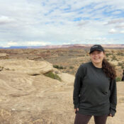 Shellby Carvalho, a female student, stands outside, poses on top of a rock structure in Canyonlands, Utah.